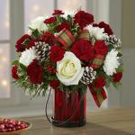 Reference # 16-C6
Starting at $ 49.99
Composed of white roses (in Deluxe, Premium and Exquisite versions only) and cushion pompons, burgundy carnations, Christmas greens with holly berries and "frosted" pinecones, this arrangement is accented with bright tartan bows in a ruby-hued glass "lantern" va